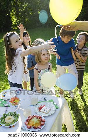 Stock Photograph - Handing out balloons at children's birthday party. Fotosearch