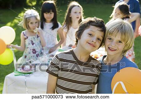 Stock Image - Young friends together at outdoor birthday party, portrait. Fotosearch