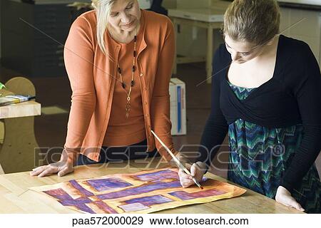 Art student painting with watercolors while teacher observes View Large Photo Image Stock Photo - Art student painting with watercolors while teacher observes. Fotosearch