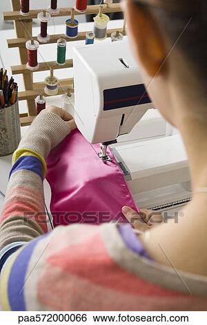 Stock Photograph - Seamstress sewing on sewing machine. Fotosearch