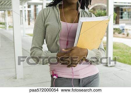Student listening to MP3 player, carrying notebook, cropped View Large Photo Image Picture - Student listening to MP3 player, carrying notebook, cropped. Fotosearch