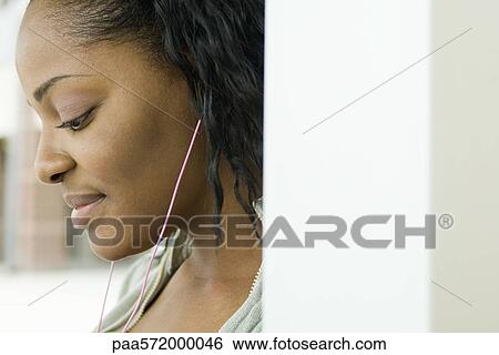Stock Photograph - Young woman listening to MP3 player. Fotosearch