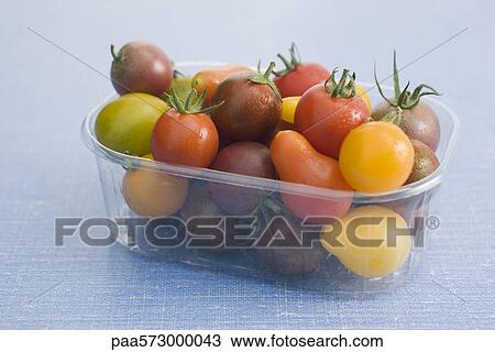 Stock Image - Assorted cherry and plum tomatoes in plastic container. Fotosearch