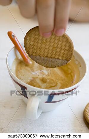 Dipping wafer in cup of cappuccino View Large Photo Image Stock Photo - Dipping wafer in cup of cappuccino. Fotosearch