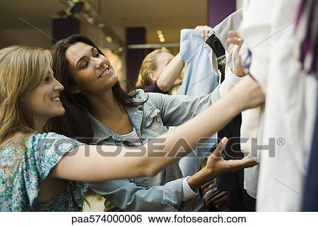 Friends looking at clothing on rack in store View Large Photo Image Stock Photograph - Friends looking at clothing on rack in store. Fotosearch