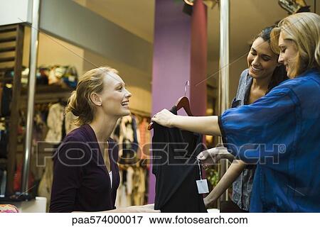 Stock Photo - Friends shopping in clothing boutique. Fotosearch