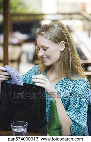 Stock Image - Woman looking in shopping bag. Fotosearch
