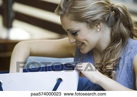 Stock Image - Woman looking in shopping bag. Fotosearch