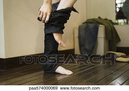 Stock Photo - Woman trying on jeans in fitting room. Fotosearch
