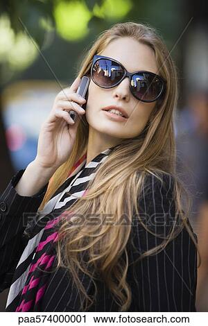 Stock Image - Young woman talking on cell phone, portrait. Fotosearch