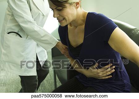 Doctor assisting patient with severe abdominal pain View Large Photo Image Stock Photo - Doctor assisting patient with severe abdominal pain. Fotosearch