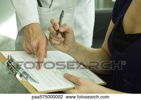 Doctor assisting patient with completing medical paperwork View Large Photo Image Stock Image - Doctor assisting patient with completing medical paperwork. Fotosearch