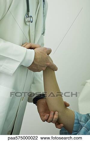 Stock Image - Doctor examining patient's arm. Fotosearch