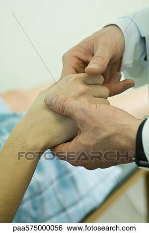 Stock Photograph - Doctor examining patient's fingers. Fotosearch