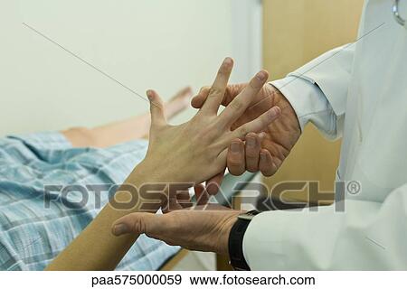 Stock Photo - Doctor examining patient's hand. Fotosearch