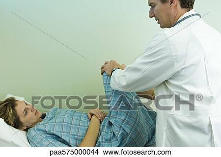 Picture - Doctor examining patient's leg and knee joint flexibility. Fotosearch