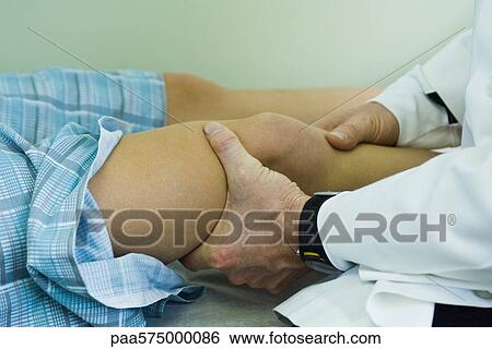Stock Photograph - Doctor examining patient's leg and knee. Fotosearch