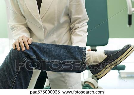 Doctor examining patient's leg and knee joint flexibility View Large Photo Image Stock Photography - Doctor examining patient's leg and knee joint flexibility. Fotosearch