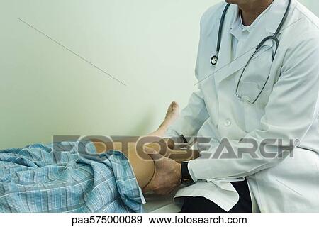Stock Photo - Doctor examining patient's leg. Fotosearch