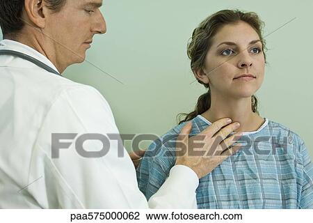 Stock Image - Doctor examining patient's neck glands. Fotosearch