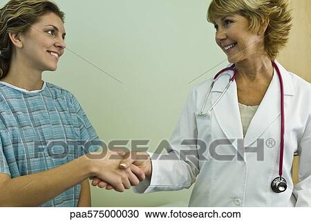 Doctor shaking hands with patient, both smiling View Large Photo Image Stock Image - Doctor shaking hands with patient, both smiling. Fotosearch