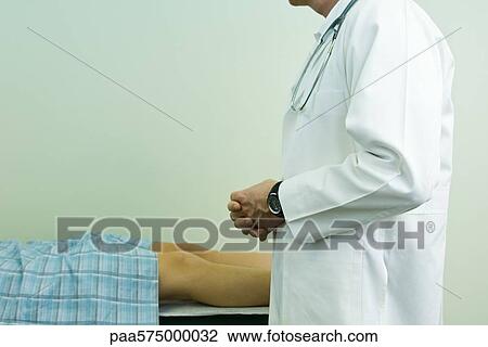 Doctor speaking to patient lying on examination table View Large Photo Image Stock Image - Doctor speaking to patient lying on examination table. Fotosearch