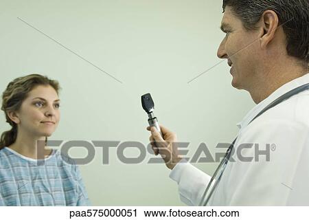 Doctor with ophthalmoscope conducting medical exam View Large Photo Image Stock Image - Doctor with ophthalmoscope conducting medical exam. Fotosearch