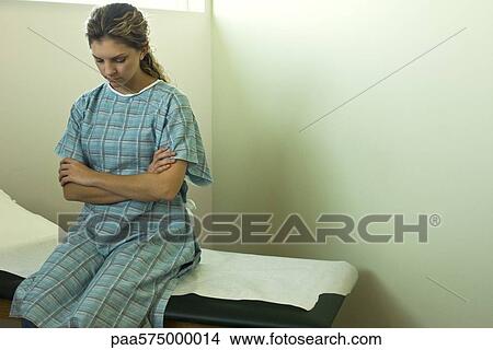 Female patient sitting on examination table waiting for doctor View Large Photo Image Picture - Female patient sitting on examination table waiting for doctor. Fotosearch