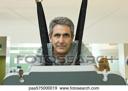 Man exercising on treadmill with assistance of rehabilitation harness supporting body weight View Large Photo Image Stock Photo - Man exercising on treadmill with assistance of rehabilitation harness supporting body weight. Fotosearch