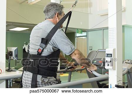 Man exercising on treadmill with assistance of rehabilitation harness supporting body weight View Large Photo Image Stock Photo - Man exercising on treadmill with assistance of rehabilitation harness supporting body weight. Fotosearch