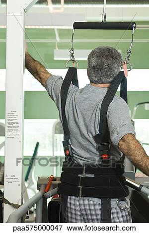 Man exercising with assistance of rehabilitation harness supporting body weight View Large Photo Image Stock Photo - Man exercising with assistance of rehabilitation harness supporting body weight. Fotosearch