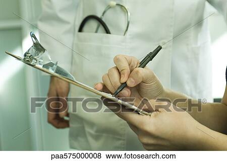 Stock Photo - Patient completing medical paperwork. Fotosearch