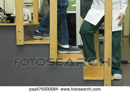 Patient practicing going down steps as part of rehabilitation exercise View Large Photo Image Picture - Patient practicing going down steps as part of rehabilitation exercise. Fotosearch
