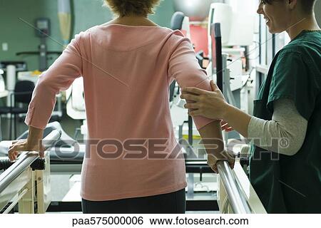 Patient undergoing rehabilitation walking exercises with assistance from physical therapist View Large Photo Image Stock Photograph - Patient undergoing rehabilitation walking exercises with assistance from physical therapist. Fotosearch