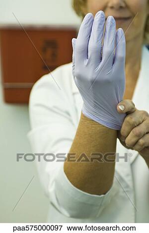 Stock Photo - Putting on disposable latex glove. Fotosearch