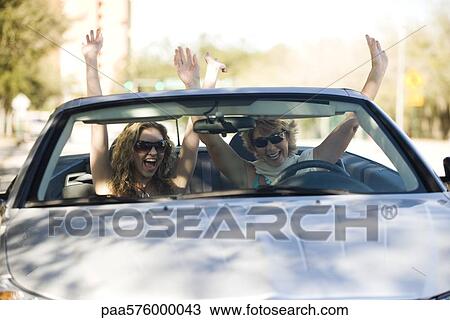 Friends riding in convertible with arms raised in the air View Large Photo Image Stock Image - Friends riding in convertible with arms raised in the air. Fotosearch