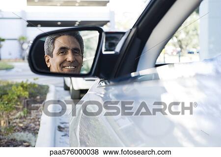 Man sitting in parked car, reflection in side-view mirror View Large Photo Image Stock Photo - Man sitting in parked car, reflection in side-view mirror. Fotosearch