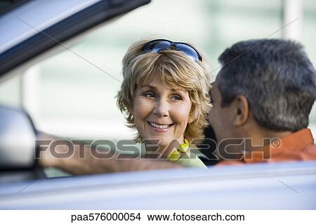 Picture - Mature couple in car together, focus on woman. Fotosearch