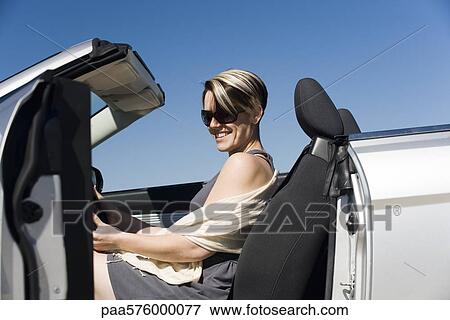 Woman getting into convertible View Large Photo Image Stock Photo - Woman getting into convertible. Fotosearch