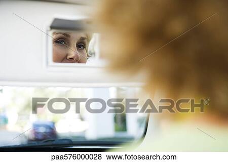 Woman in car looking at self in visor vanity mirror View Large Photo Image Stock Photo - Woman in car looking at self in visor vanity mirror. Fotosearch