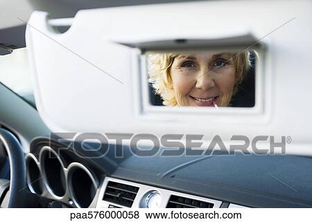 Woman In Car Using Visor Vanity Mirror To Put On Make Up Stock Photo Paa576000058 Fotosearch