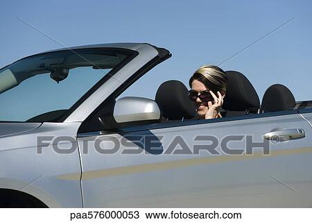 Woman in convertible, lowering sunglasses to look at camera View Large Photo Image Stock Image - Woman in convertible, lowering sunglasses to look at camera. Fotosearch