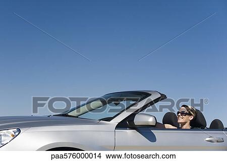 Picture - Woman out for pleasure drive in convertible. Fotosearch