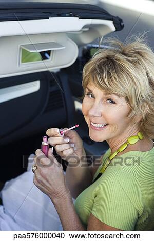 Woman putting on makeup in car using visor vanity mirror View Large Photo Image Stock Image - Woman putting on makeup in car using visor vanity mirror. Fotosearch