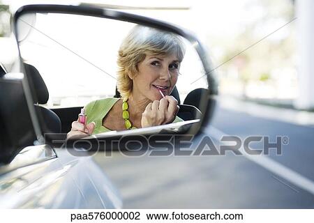 Woman putting on makeup, reflection in side-view mirror View Large Photo Image Stock Image - Woman putting on makeup, reflection in side-view mirror. Fotosearch