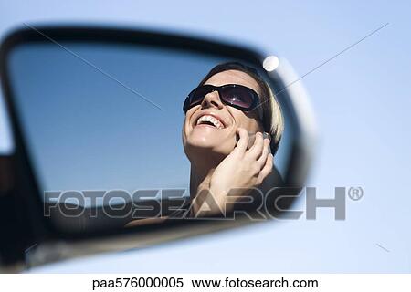 Woman talking on cell phone, reflection in side-view mirror View Large Photo Image Stock Photography - Woman talking on cell phone, reflection in side-view mirror. Fotosearch