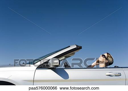 Stock Photograph - Woman talking on cell phone while driving convertible. Fotosearch