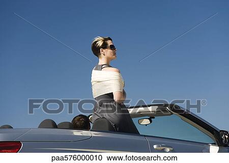 Young woman standing up in convertible looking at view View Large Photo Image Stock Image - Young woman standing up in convertible looking at view. Fotosearch