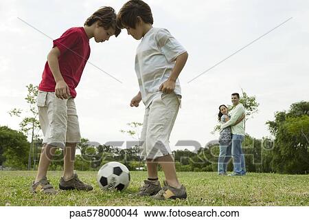 Boys playing soccer, parents embracing in background View Large Photo Image Picture - Boys playing soccer, parents embracing in background. Fotosearch