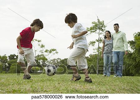 Boys playing soccer, parents watching in background View Large Photo Image Stock Photograph - Boys playing soccer, parents watching in background. Fotosearch